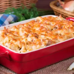 Zapiekanka makaronowa z serem w czerwonym naczyniu.
