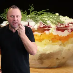 Mężczyzna degustuje warstwową sałatkę, która wygląda jak śledzie pod pierzynką. Przepis na tę pyszną potrawę jest w zasięgu ręki!