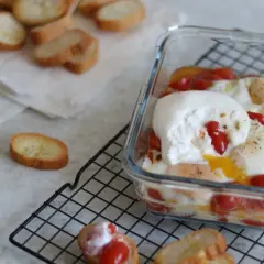 Pyszna burrata z piekarnika z jajkami i pomidorkami, podana z grzankami.
