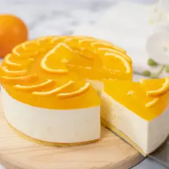 Sernik pomarańczowy z mascarpone, ozdobiony plasterkami pomarańczy, wygląda apetycznie. Kawałek ciasta został już odkrojony.