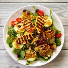 Pyszna sałatka z grillowanym halloumi, rukolą, pomidorkami, ogórkiem i słonecznikiem, polana sosem musztardowym.