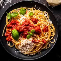 Talerz spaghetti z sosem pomidorowym, parmezanem i bazylią.
