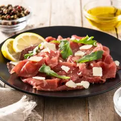 Carpaccio wołowe jak jeść: cienkie plastry surowej wołowiny z parmezanem, rukolą i cytryną. Idealne na lekki posiłek.