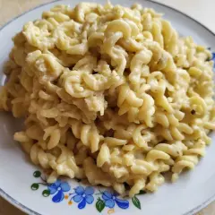 Pyszny makaron fusilli w kremowym sosie pieczarkowym, podany na talerzu z niebieskimi kwiatami.