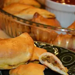Złociste pierogi pieczone z kurczakiem gyros, jeden przekrojony, ukazujący aromatyczne nadzienie.