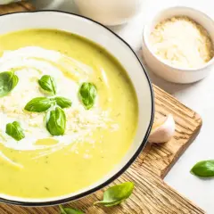 Aksamitna zupa krem z cukinii z warzywami, udekorowana listkami bazylii i parmezanem. Idealna na lekki obiad.