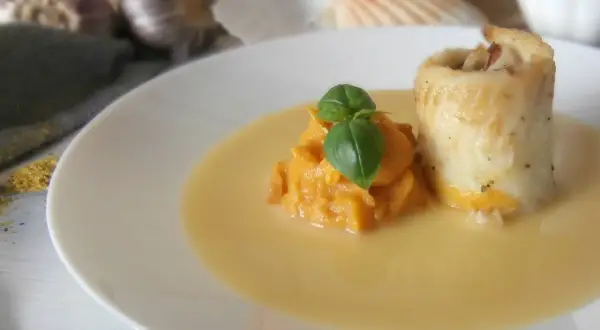 Roladka rybna z puree z dyni, udekorowana bazylią, podana w kremowym sosie beurre blanc.