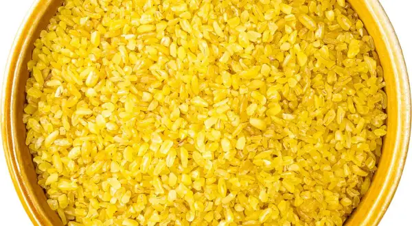 Żółta kasza bulgur w ceramicznej misce. Idealna do przygotowania pysznego posiłku, np. jak ugotować kaszę bulgur w woreczku.