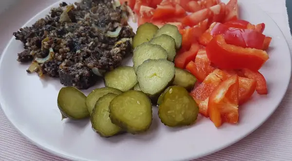 Kaszanka z cebulką, ogórki kiszone, pomidory i papryka. Czy można jeść surową kaszankę? To pytanie pozostaje otwarte.