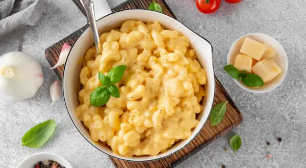 Pyszne, kremowe mac and cheese w białej misce, z bazylią i pomidorkami koktajlowymi. Idealne, gdy zastanawiasz się, jak podgrzać mac and cheese.