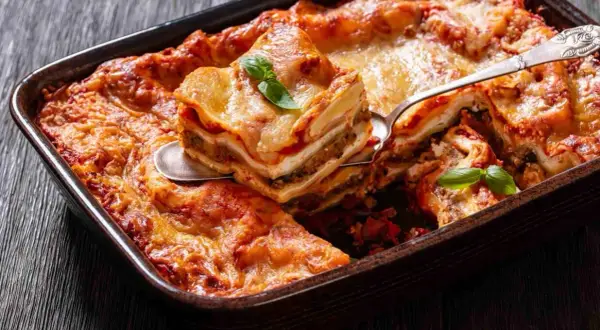Pyszne lasagne z warzywami, zrumienione i pachnące, podane na drewnianym blacie. Idealne danie na rodzinny obiad.