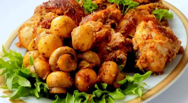 Pyszny kurczak z pieczarkami i ziemniaczkami, podany na liściach sałaty. Danie wygląda jakby było przygotowane z kapustą kiszoną.