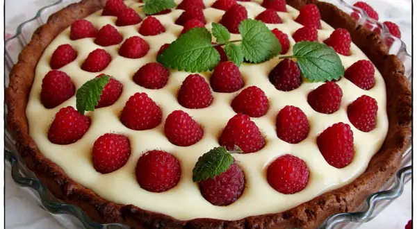 Tarta z mascarpone i białą czekoladą, ozdobiona malinami i miętą. Kwestia smaku, która zachwyca!