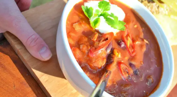 Aksamitna zupa meksykańska z pulpecikami, ozdobiona kleksem śmietany i świeżą kolendrą, z plasterkami chili.