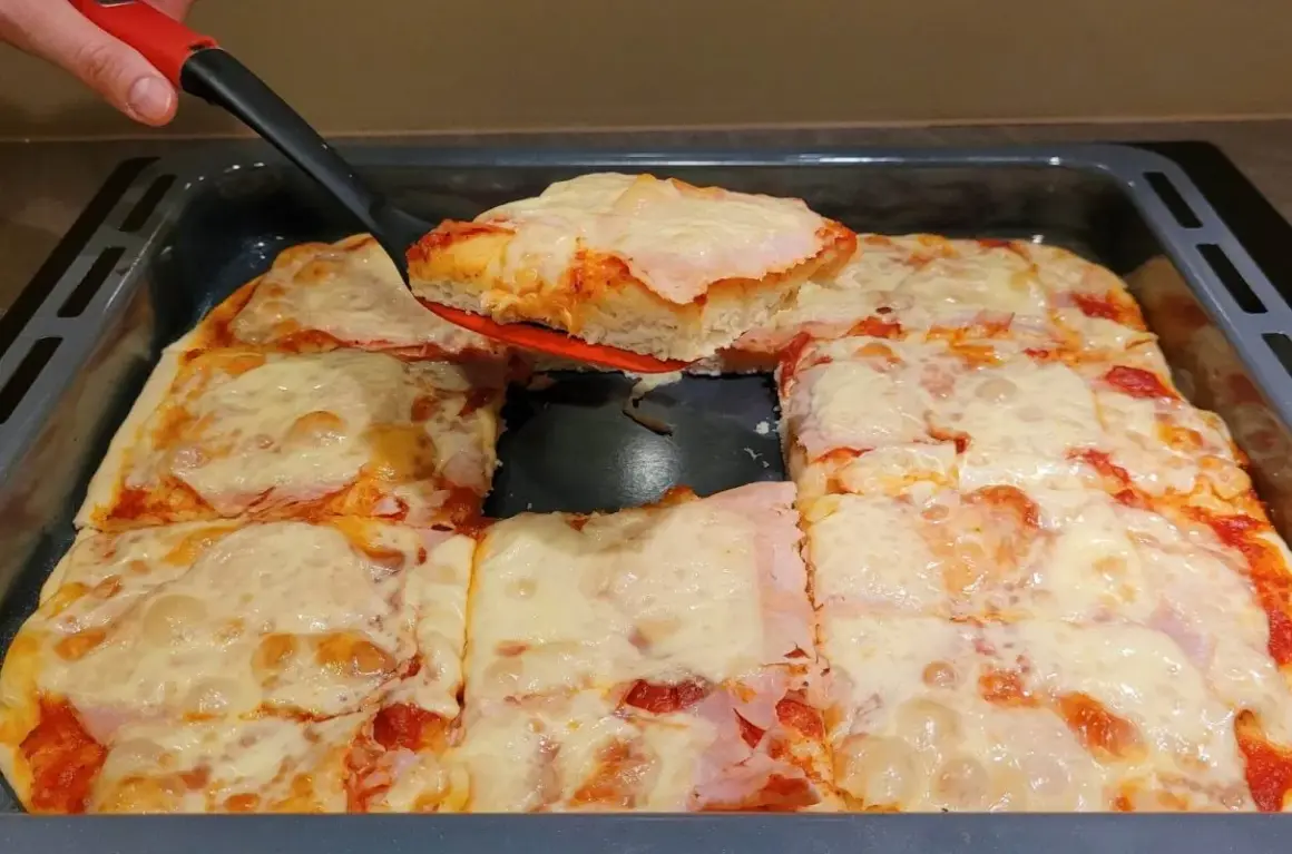 Pyszna, domowa pizza z blachy, z ciągnącym się serem i szynką, właśnie kroimy pierwszy kawałek.