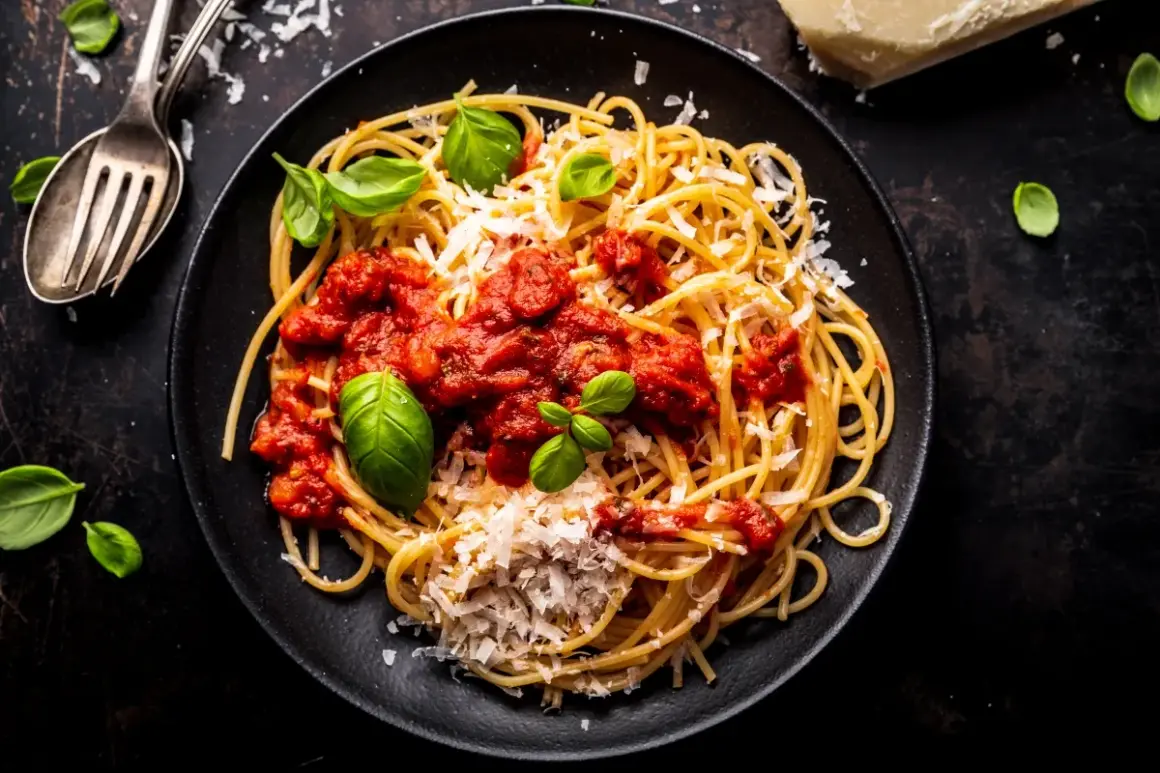 Talerz spaghetti z sosem pomidorowym, parmezanem i bazylią.