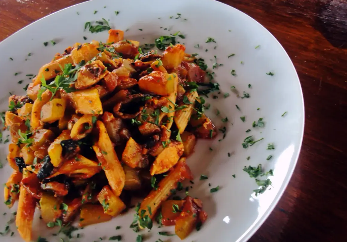 Penne z kurczakiem i cukinią w sosie pomidorowym, posypane natką pietruszki. Pyszne danie na obiad.