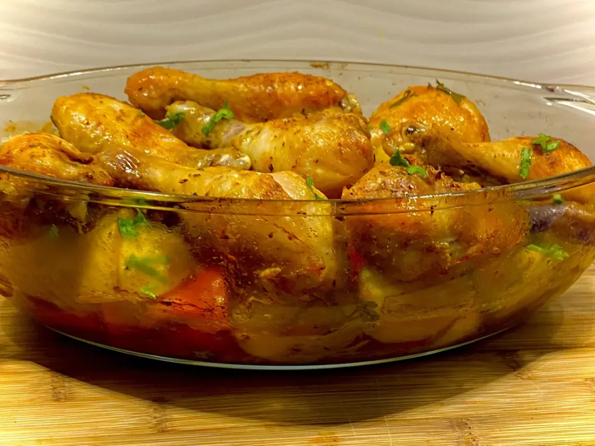 Pyszny kurczak zapiekany z warzywami w szklanej formie, skropiony ziołami.