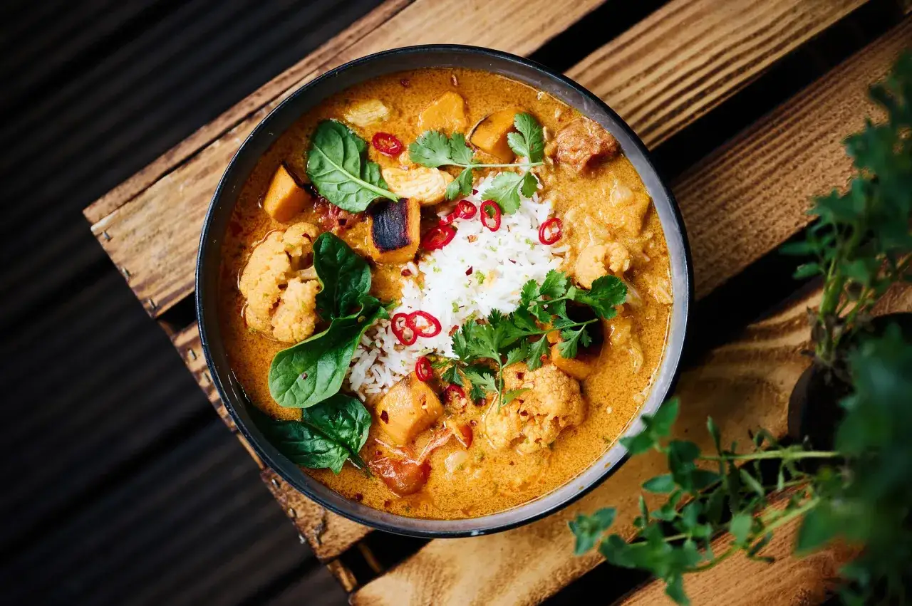 Aksamitny sos do kurczaka z ryżem, kalafiorem i batatami, ozdobiony chili i kolendrą. Idealny przepis na obiad.