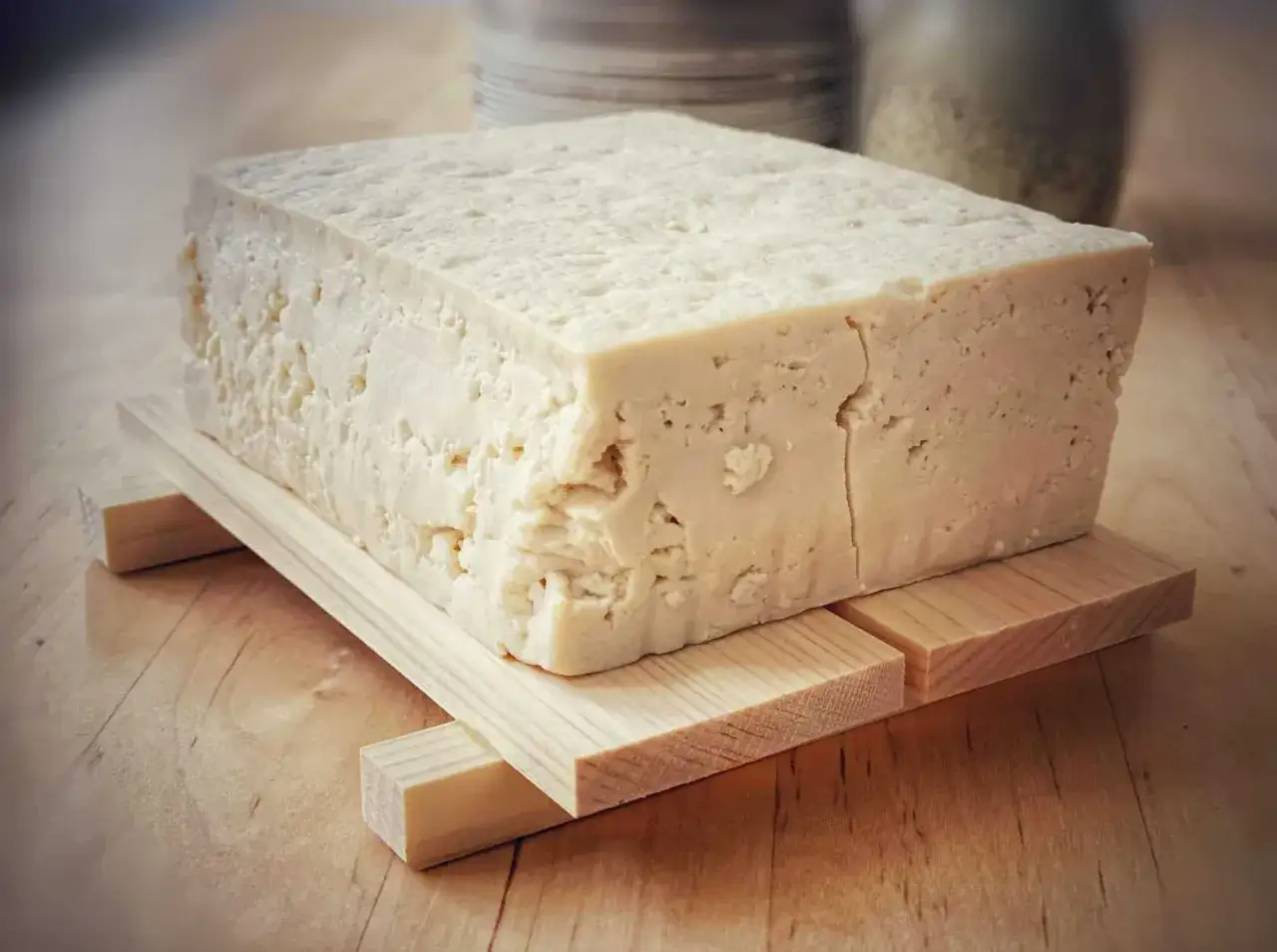 Kostka świeżego, domowego tofu na drewnianej podstawce. Idealny składnik, by dowiedzieć się, jak zrobić tofu.