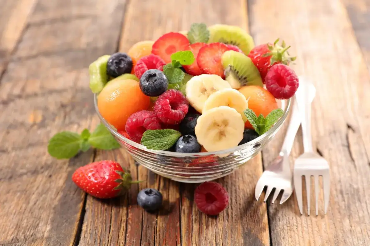Kolorowa sałatka z owocami: truskawki, maliny, borówki, banany, kiwi i melon. Idealna na letni deser.